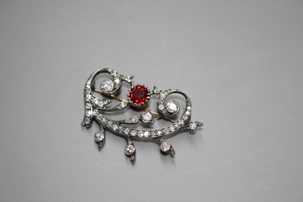 An early 20th century yellow and white metal, red spinel and diamond set foliate scroll brooch,
